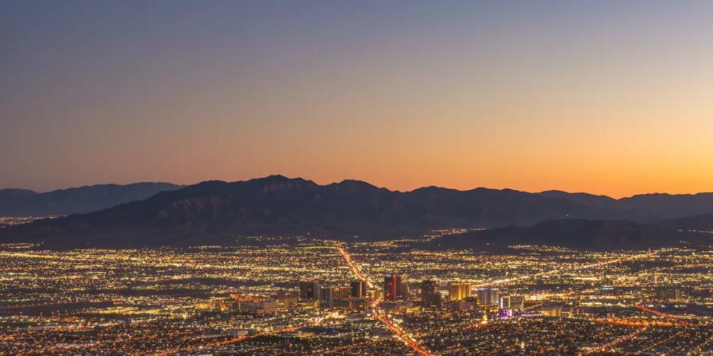 Rozświetlona pustynna dolina Las Vegas o zmierzchu, neonowe wieże Stripu wyrastające z pustyni Mojave