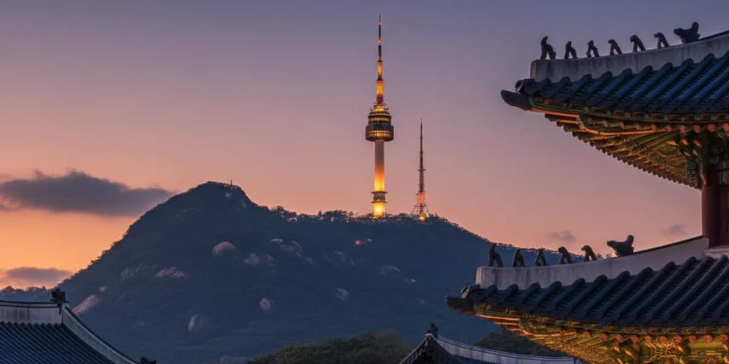 Linie dachów pałacu Gyeongbokgung na pierwszym planie z wieżą N Seoul Tower górującą na Namsanie w tle
