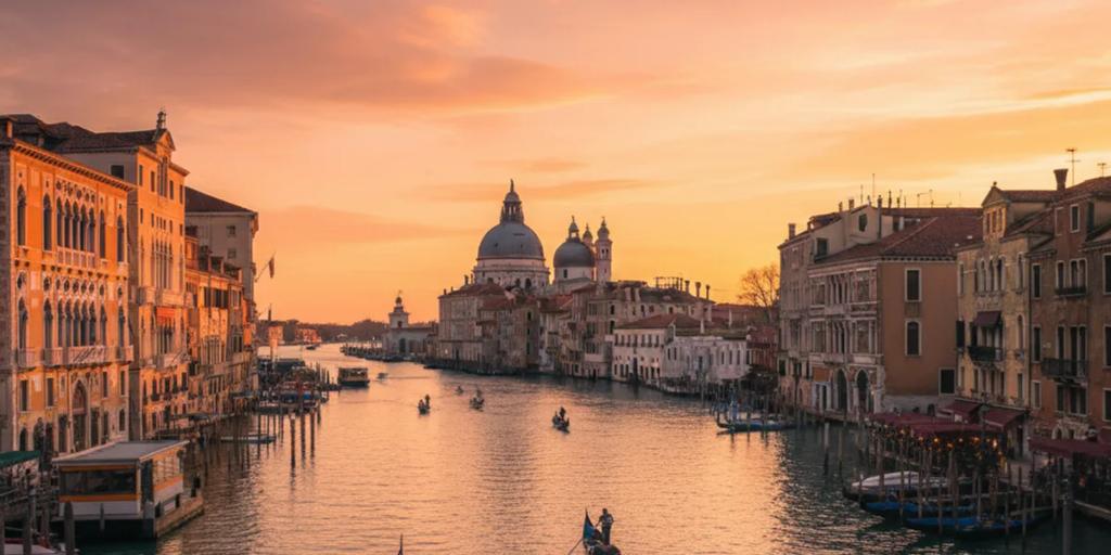 Gondole zacumowane na Canal Grande o zmierzchu z kopułami kościoła Salute w tle
